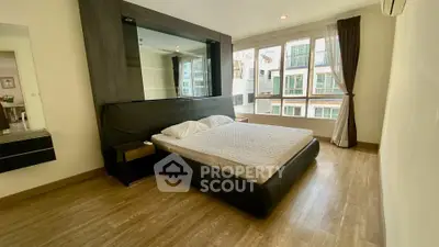 Spacious bedroom with large windows and modern decor in a luxury apartment.