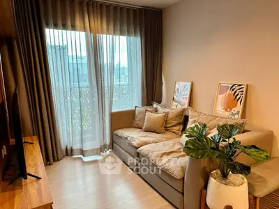 Cozy living room with plush sofa, stylish decor, and large window offering natural light.