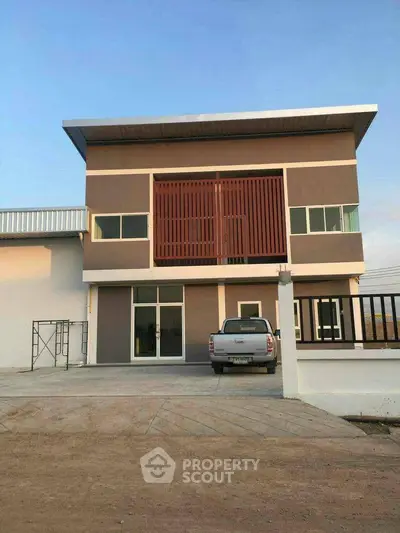 Modern two-story building with large windows and parking space in front.