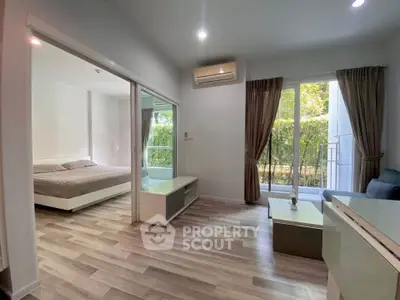 Modern living room with view into cozy bedroom and garden access