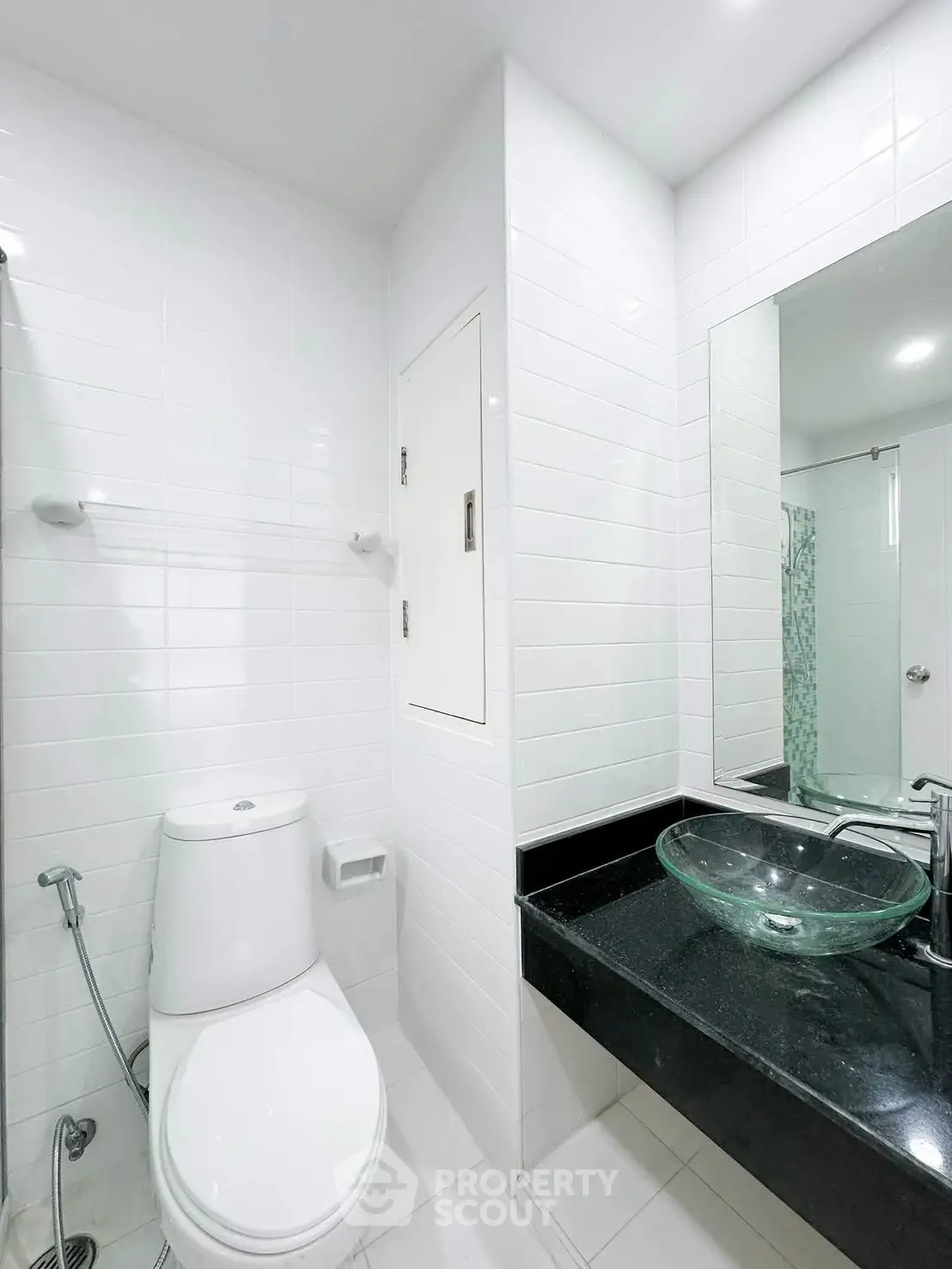 Modern bathroom with sleek glass sink and white tiles, featuring a contemporary design and bright lighting.
