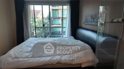 Cozy bedroom with large window and modern decor, offering natural light and a comfortable atmosphere.