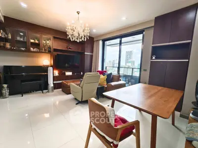 Spacious living room with city view, elegant chandelier, and modern furnishings.