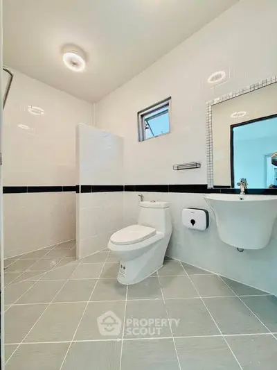 Modern bathroom with sleek design, featuring a toilet, sink, and tiled walls and floor.