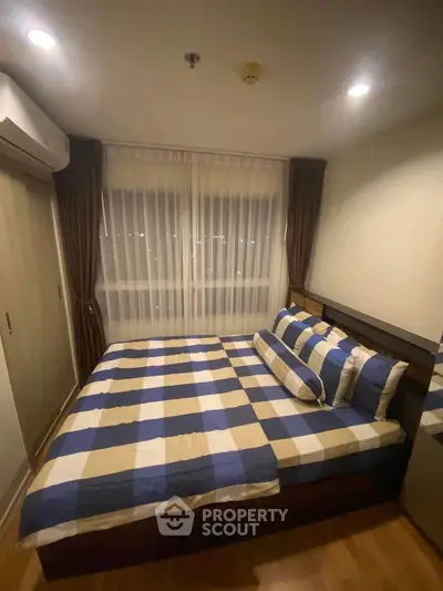 Cozy bedroom with large window and stylish checkered bedding in modern apartment.