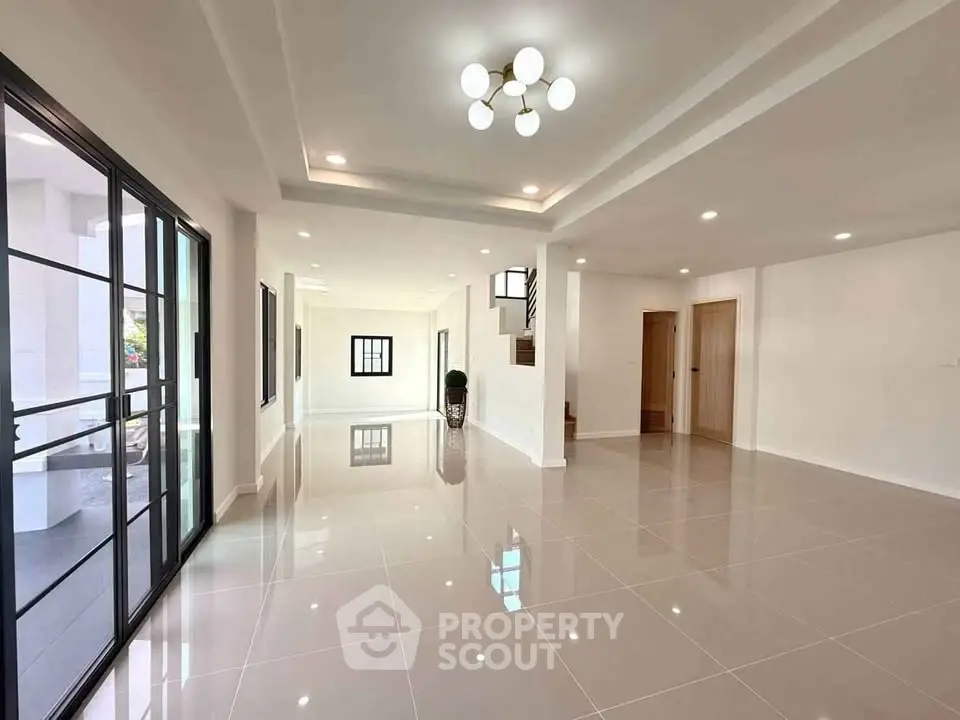 Spacious modern living room with glossy tiled floors and elegant lighting.