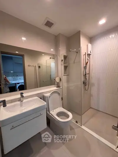 Modern bathroom with sleek fixtures and glass shower enclosure in contemporary apartment.