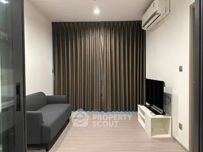 Modern living room with sleek sofa, flat-screen TV, and air conditioning in a stylish apartment.