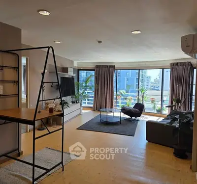 Spacious living room with large windows and modern decor in urban apartment.