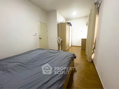 Spacious bedroom with modern wooden flooring and ample storage space.