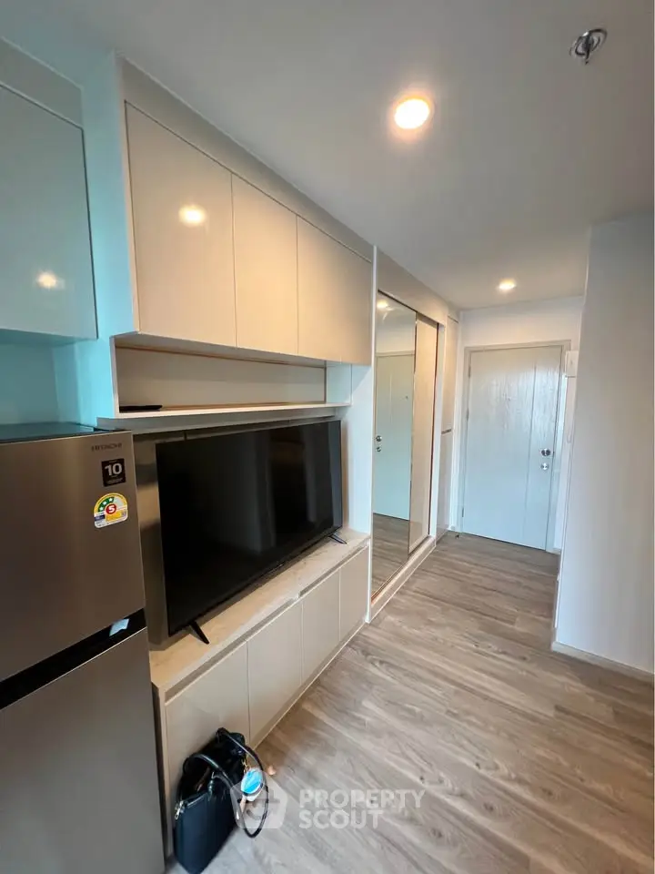 Modern apartment interior with sleek cabinets and large TV, showcasing stylish living space.