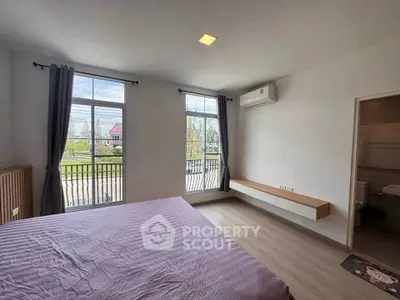Spacious bedroom with large windows and balcony view, featuring modern air conditioning.
