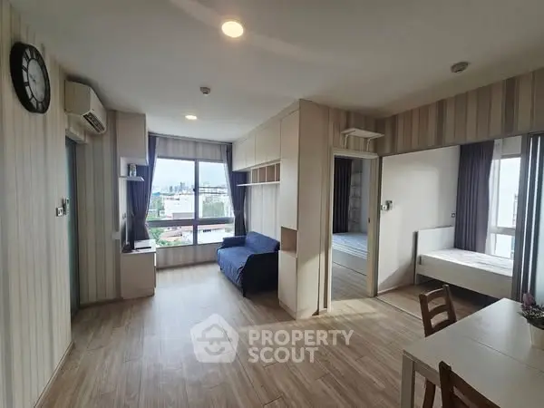 Modern living room with wooden flooring and city view, featuring a cozy seating area and dining space.