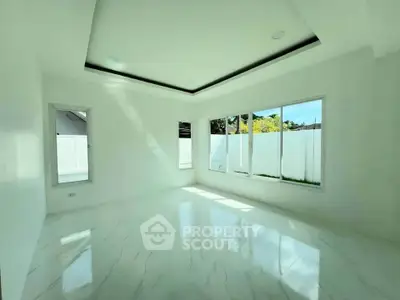 Spacious sunlit room with large windows and elegant marble flooring in modern home.