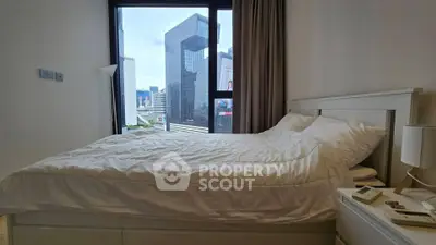 Modern bedroom with city view, featuring a cozy bed and large window in a high-rise apartment.