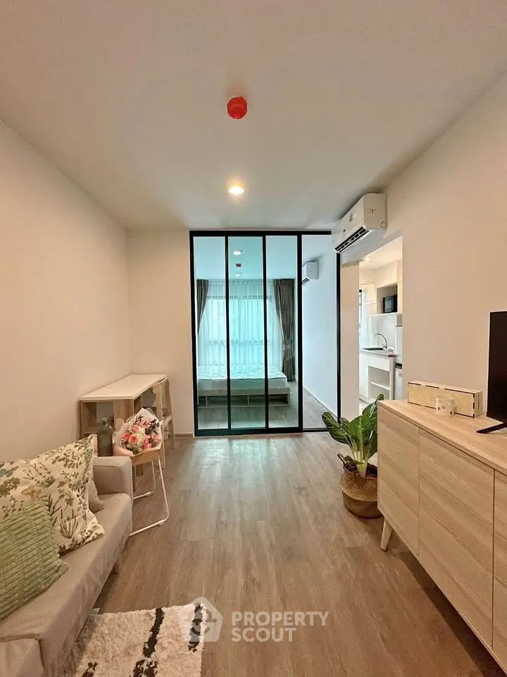 Modern living room with sliding glass doors leading to a cozy bedroom, featuring stylish decor and natural light.