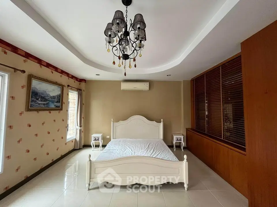 Spacious bedroom with elegant chandelier and classic wooden accents
