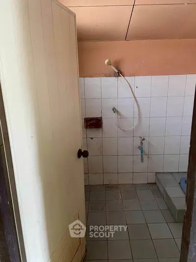 Simple bathroom with shower and tiled floor, ideal for renovation.