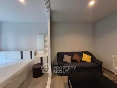 Modern studio apartment with cozy living area and stylish bedroom separated by glass partition.