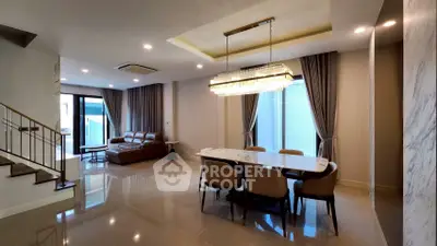 Luxurious open-plan living and dining area with elegant chandelier and modern furnishings.