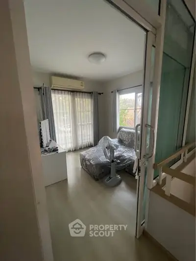 Cozy living room with covered furniture and large windows for natural light.