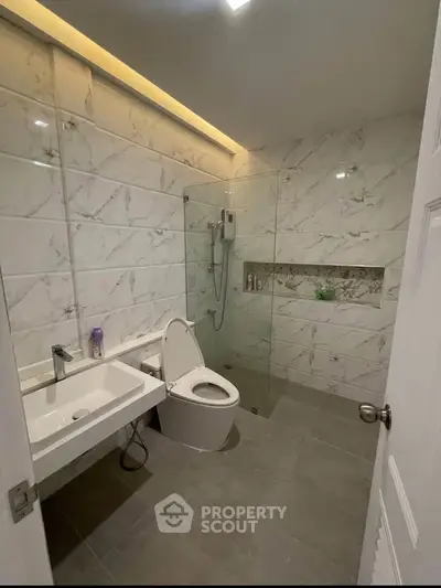 Modern bathroom with marble tiles and glass shower enclosure