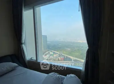 Stunning bedroom with panoramic city view through large window, perfect for urban living.