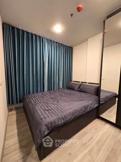 Modern bedroom with elegant blue curtains and sleek mirrored wardrobe