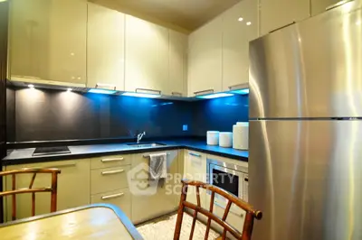 Modern kitchen with sleek cabinets, stainless steel fridge, and ambient lighting