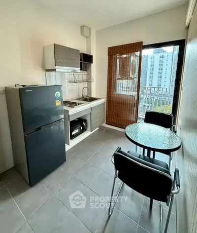 Modern kitchen with compact dining area and balcony view in urban apartment.