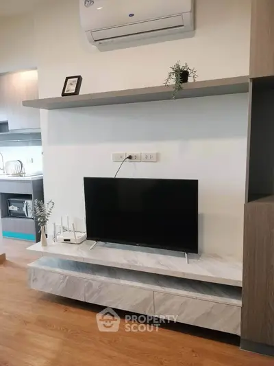 Modern living room with sleek TV setup and stylish shelving, featuring elegant wood flooring and contemporary decor.