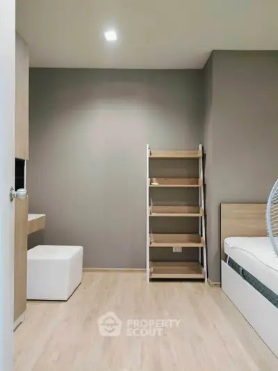 Modern minimalist bedroom with wooden flooring and sleek shelving unit.