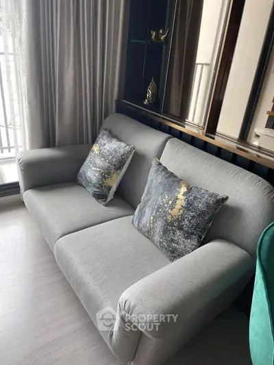 Modern living room with stylish gray sofa and decorative pillows, featuring elegant floor-to-ceiling curtains.
