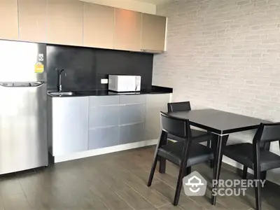 Modern kitchen with sleek cabinetry and stainless steel appliances, complemented by a chic dining set and stylish brick accent wall.