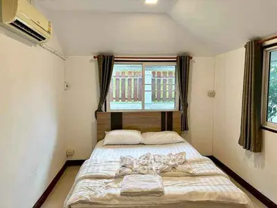 Cozy bedroom with double bed, air conditioning, and natural light from windows.