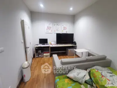 Cozy living room with modern decor and wooden flooring, featuring a comfortable sofa and entertainment setup.