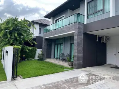 Modern two-story house with balcony and lush green lawn