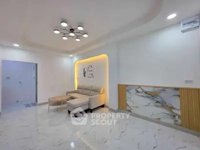 Modern living room with elegant lighting and marble accents, featuring a cozy sofa and stylish decor.