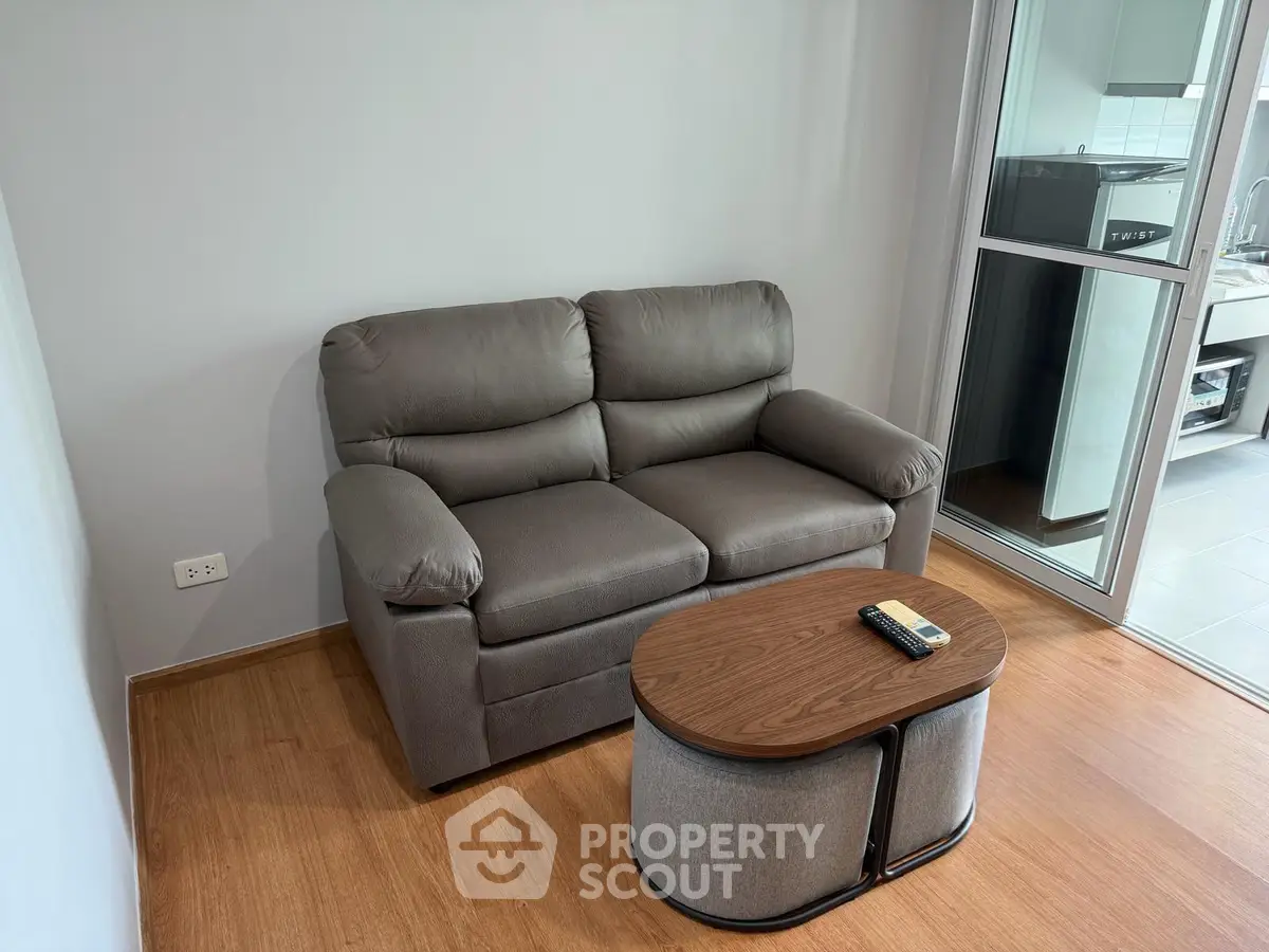 Cozy living room with plush sofa and modern coffee table, adjacent to a sleek kitchen area.