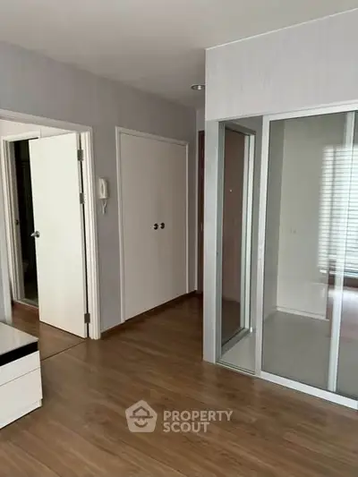 Spacious modern apartment interior with wooden flooring and glass partition.