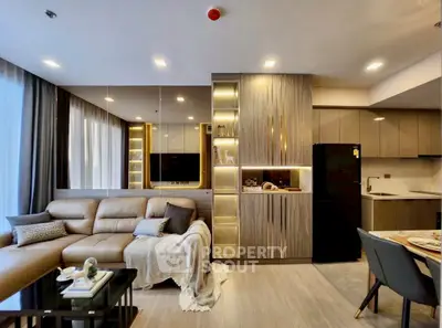 Modern living room with elegant decor and open kitchen layout, featuring a cozy sofa and stylish lighting.