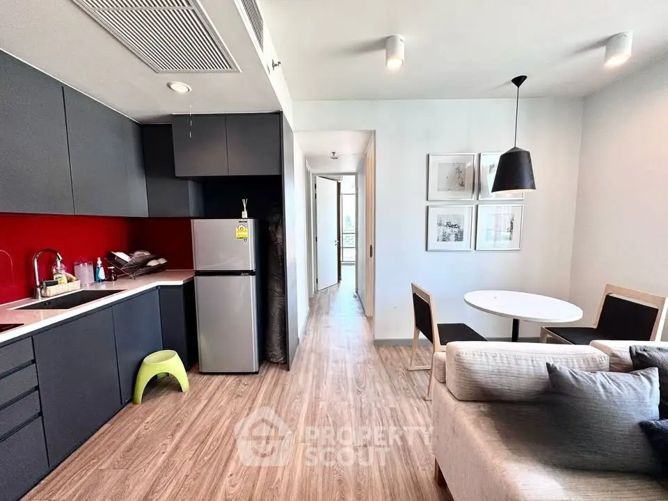 Modern open-layout kitchen and living area with sleek design and vibrant red backsplash.