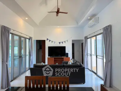 Spacious living room with high ceiling, modern furniture, and large windows for natural light.
