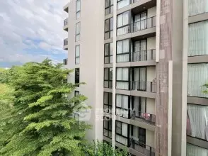 Modern apartment building with large windows and lush greenery