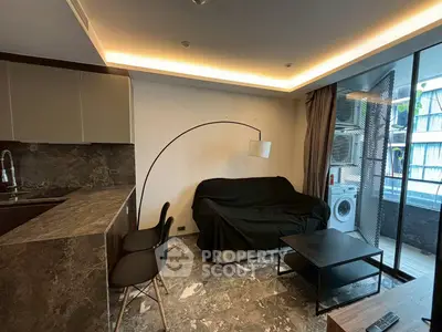 Modern living room with sleek kitchen and balcony view, featuring stylish furniture and elegant lighting.