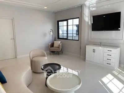 Modern living room with sleek furniture and wall-mounted TV, featuring large windows for natural light.