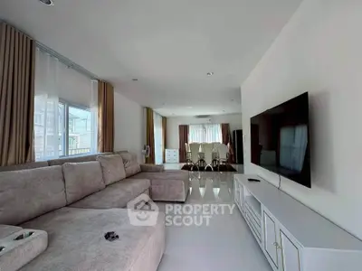 Spacious modern living room with large sofa and flat-screen TV, perfect for relaxation.