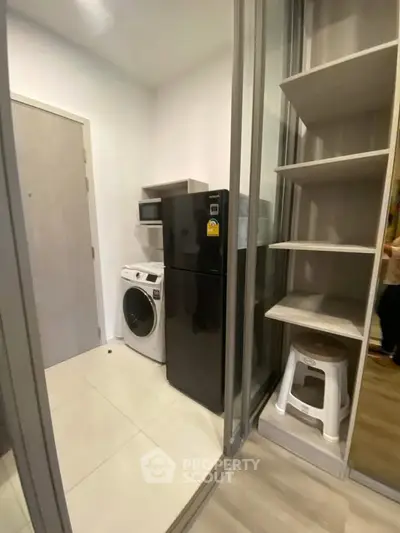 Compact laundry and storage area with modern appliances and shelving in a sleek apartment.