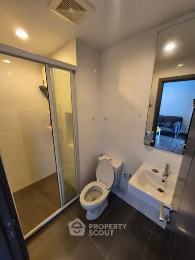 Modern bathroom with shower, toilet, and sink in a sleek apartment.
