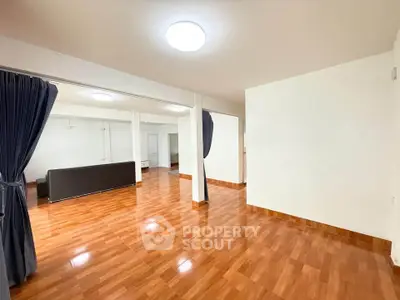 Spacious open-plan living area with polished wooden floors and modern lighting.